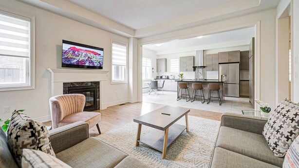 A spacious living room with a fireplace, a television, and a kitchen in the background.