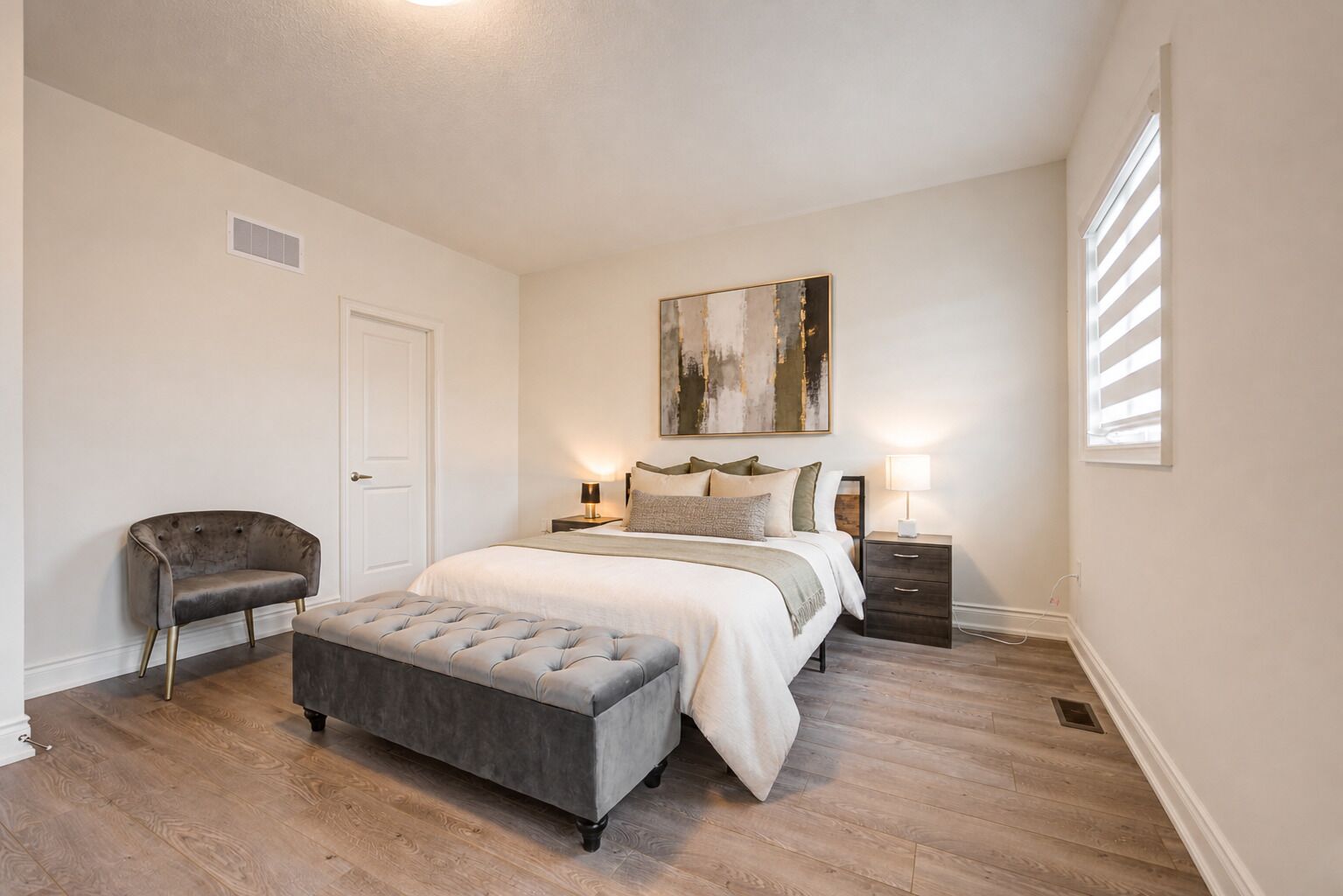 A bedroom with a bed, bedside tables, a chair, and a bench.