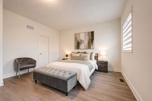 A bedroom with a bed, bedside tables, a chair, and a bench.