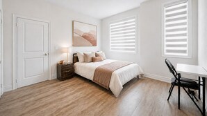 A bedroom with a bed, bedside table, lamp, and a chair.