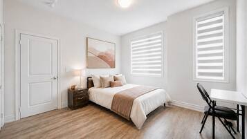 Ein Schlafzimmer mit Bett, Nachttisch, Lampe und Stuhl.