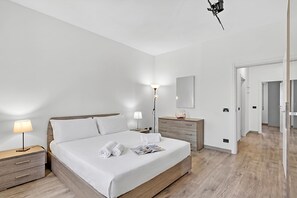 Ein modernes Hotelzimmer mit einem großen Bett, Nachttischen, einem Beistelltisch, einer Lampe, einem Schminktisch und einem Spiegel.