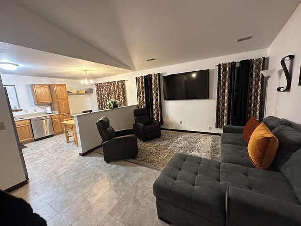 A modern living room with a grey sofa, a black armchair, and a patterned rug. - Cozy 3-bedroom bungalow in Fort Wayne (Fort Wayne)