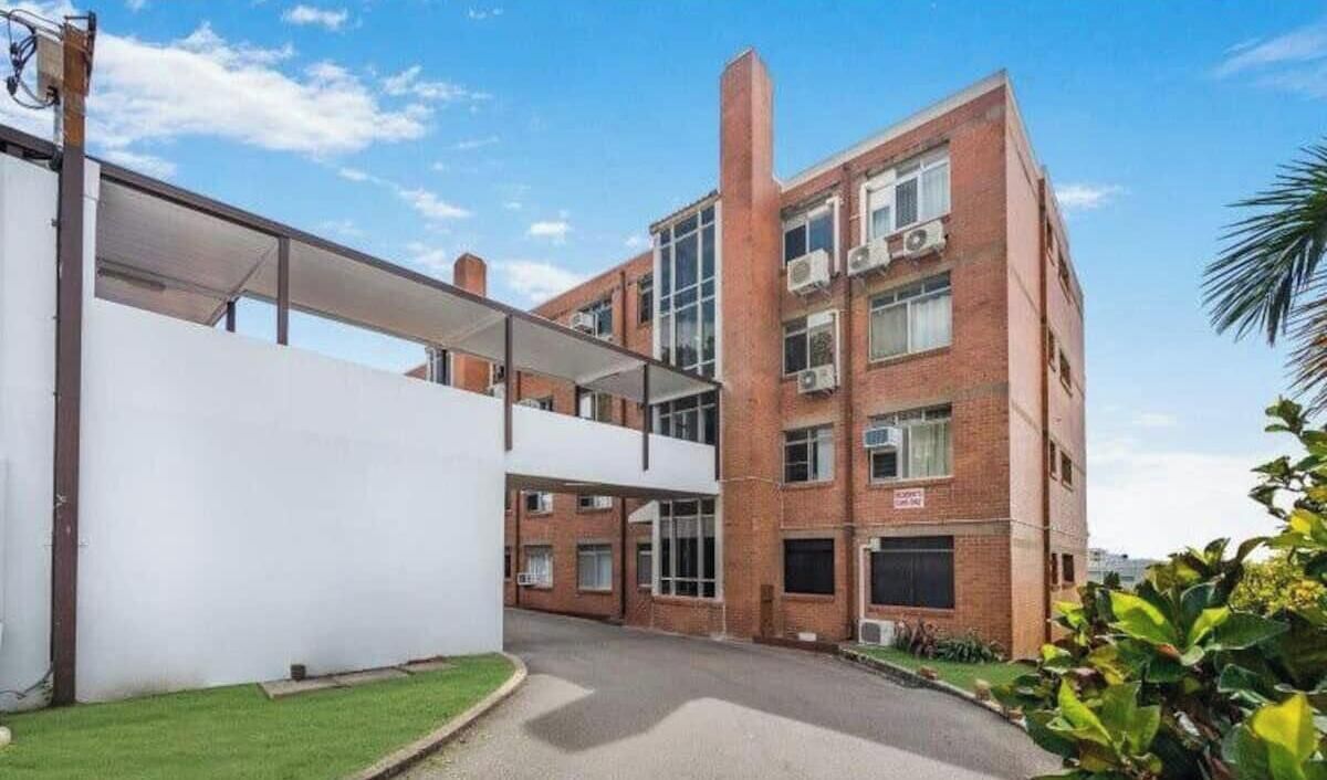 Un edificio a due piani con tetto piatto, una tettoia e facciata in mattoni.