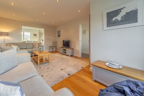 Ein modernes Wohnzimmer mit einer Sofagarnitur, einem Couchtisch, einem Fernseher und einer gerahmten Karte an der Wand.