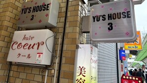 En byggnad med flera skyltar som visar ”YU’S HOUSE 3” och en betalterminal för betalningar via PayPay.