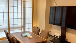 Ett konferensrum med ett träbord, stolar, en stor platt-TV och en traditionell japansk shoji-skärm.
