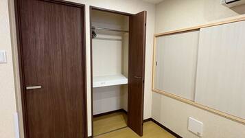 A room with a wooden wardrobe, a white shelf, and a white wardrobe with a wooden frame.