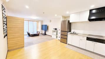 A modern kitchen with a built-in oven, microwave, and refrigerator, a dining area with a table and chairs, and a large window providing natural light.