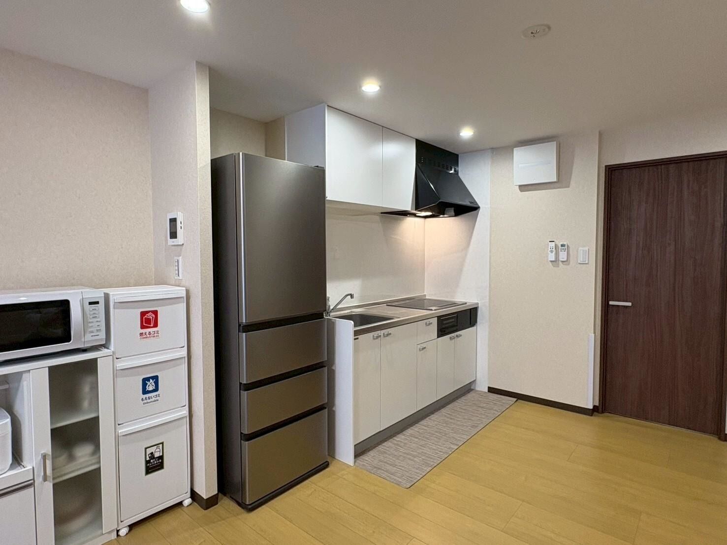 A compact kitchen with a refrigerator, microwave, and built-in oven, along with a sink and cabinets.