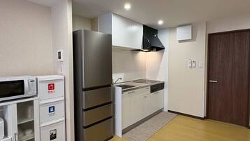 A compact kitchen with a refrigerator, microwave, and built-in oven, along with a sink and cabinets.