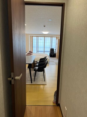 Ein Hotelzimmer mit Holzboden, einem Bett mit Kissen, einem Schreibtisch mit Stühlen und einem Massagesessel.