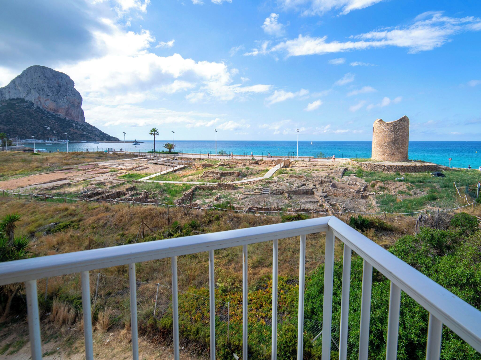 An archaeological site with ruins, a watchtower, and a coastal view.