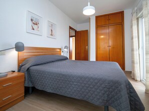 A bedroom with a bed, bedside table, lamp, wardrobe, and a picture on the wall. - Hernando I by Interhome (Calpe/Calp)