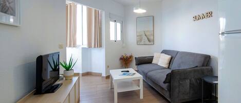 A modern living room with a sofa, a coffee table, a TV, and a potted plant.
