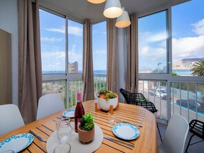 A dining area with a table set for two, a potted plant, and a bottle of wine. - Hernando I by Interhome (Calpe/Calp)
