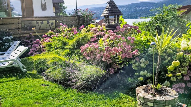 Un jardín con un pabellón, un muro de piedra y vistas a las montañas.