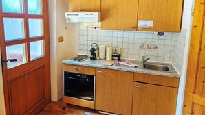 Una cocina compacta con armarios de madera, lavavajillas integrado y una ventana con vidrio esmerilado.