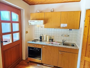 Eine kleine Küche mit Holzausstattung, Geschirrspüler und einem Fenster mit satinierten Scheiben.