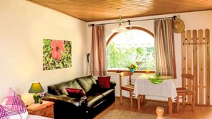 Una habitación acogedora con sofá, una mesa de comedor con sillas, cama y ventana con cortinas.