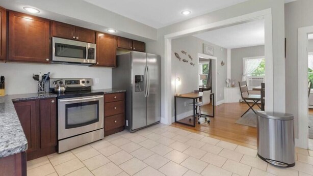 Una cocina moderna con electrodomésticos de acero inoxidable, armarios de madera y piso de baldosas.