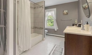 Baño con ducha, inodoro, lavabo y ventana con vista a la vegetación.