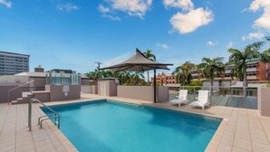 A rooftop pool with a pergola, lounge chairs, and a view of buildings and palm trees. - Elevated CBD Escape Level 6 Views & Resort Facilities (Townsville)