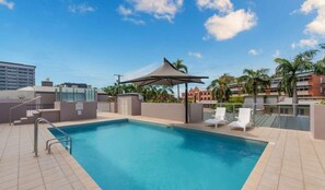 A rooftop pool with a pergola, lounge chairs, and a view of buildings and palm trees. - Elevated CBD Escape Level 6 Views & Resort Facilities (Townsville)