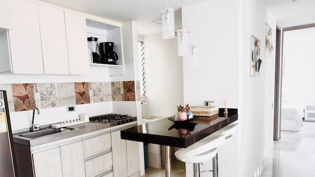 A modern kitchen with a gas stove, white cabinets, and a bar stool. - Business & Leisure Premium Apartment | Fast Wi-Fi & Prime Location (Villavicencio)