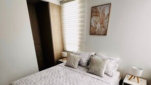 A bedroom with a bed, nightstands, a window with blinds, a door, and a wall-mounted painting. - Business & Leisure Premium Apartment | Fast Wi-Fi & Prime Location (Villavicencio)
