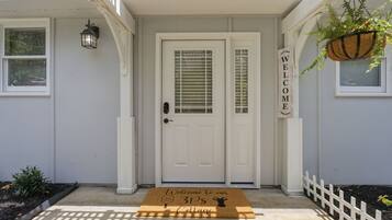 A white house with a front door, a welcome sign, and a doormat.
