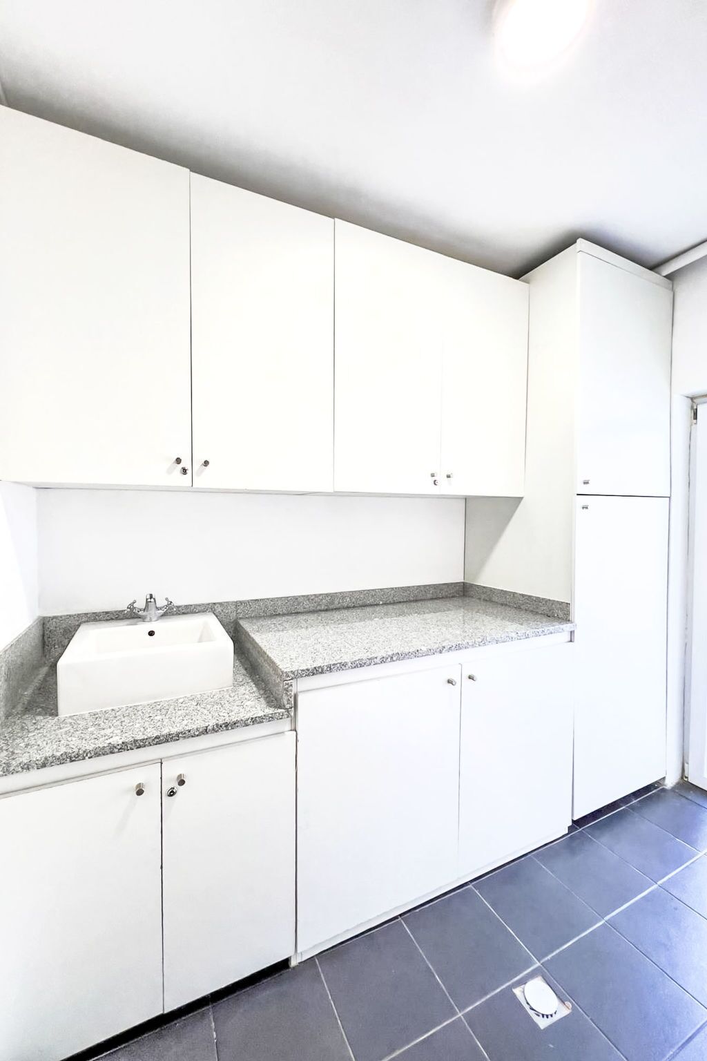 Cocina con gabinetes blancos, encimera de granito y un lavamanos.