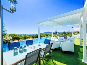 A poolside area with a table, chairs, and a pergola overlooking a pool and landscape. - Casa do Lago by Interhome (Estoi)