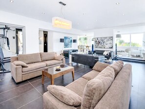 A spacious living room with a large sofa, a coffee table, and a dining area with chairs. - Casa do Lago by Interhome (Estoi)