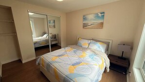 A bedroom with a bed, a nightstand, a lamp, a painting, and a closet. - Gateway to Banff | Cozy 2BR Sleeps 6 | NW Calgary (Calgary)