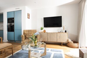 A modern living room with a sofa, a glass coffee table, and a flat-screen TV mounted on the wall. - Treth Nook - Dog friendly, 100m from beach, Parking (Harlyn Bay)