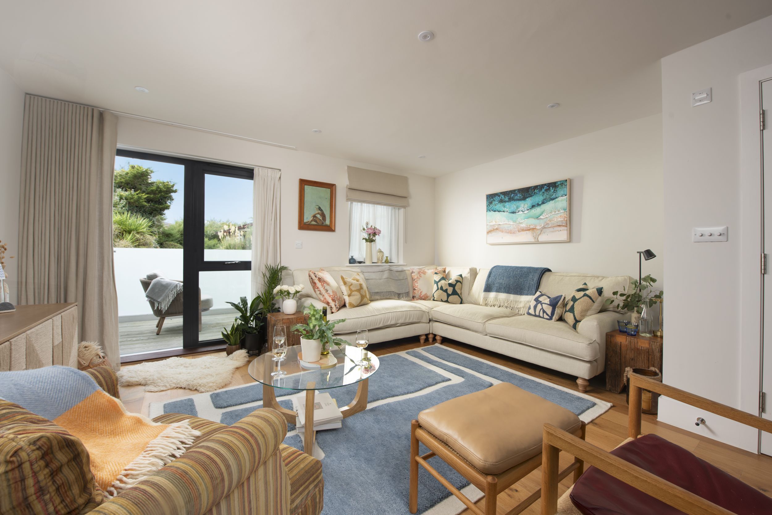 A modern living room with a sectional sofa, a glass coffee table, and a view of the outdoors.