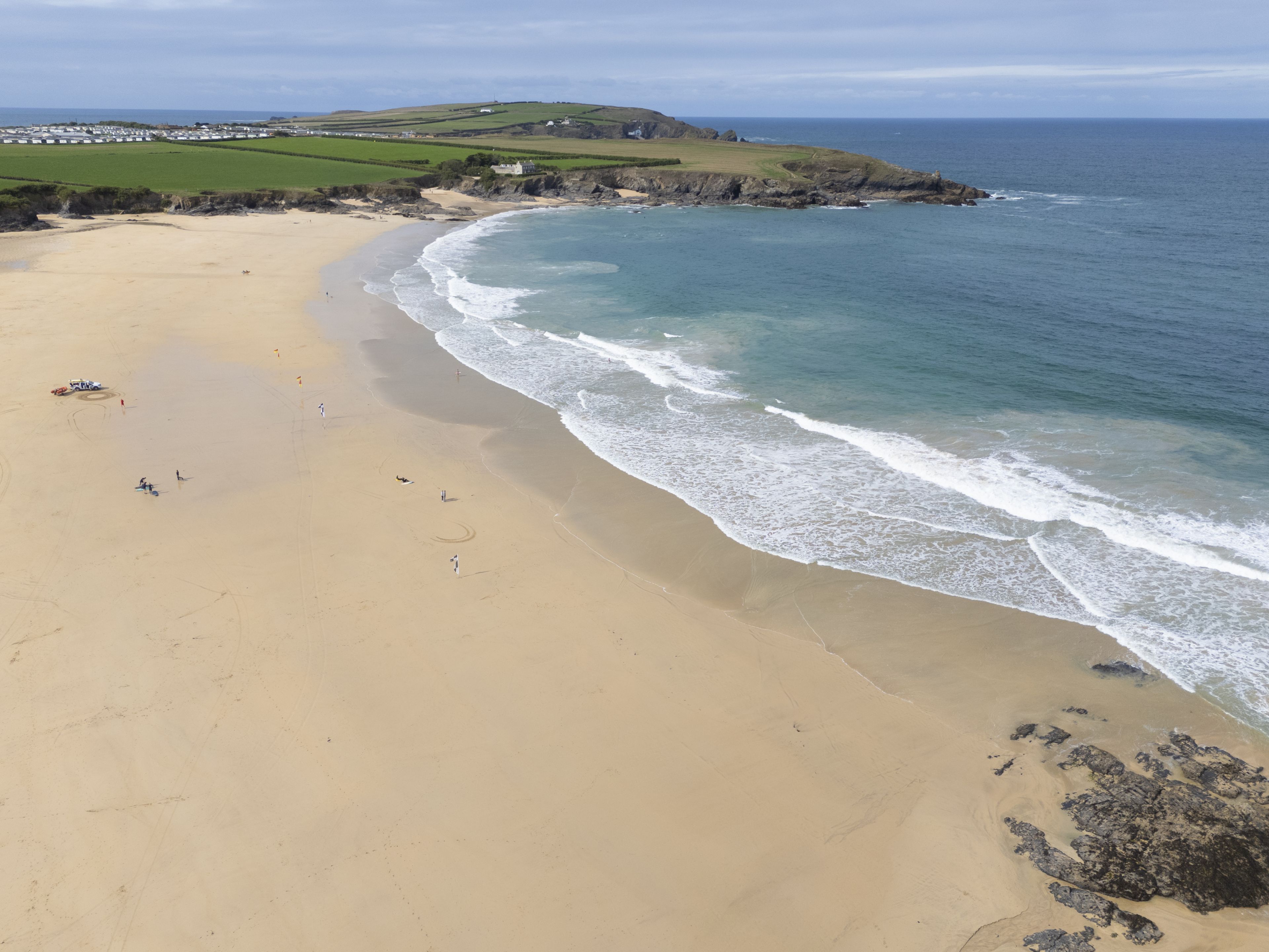 A beach with a clear view of the ocean, sandy shore, and distant hills.