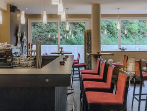 A modern bar area with a long counter, red upholstered chairs, and pendant lighting. - LoriVita by Interhome (Saalbach-Hinterglemm)