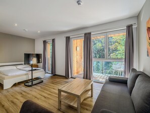 A modern living room with a sofa, a TV, a wooden coffee table, and large windows with curtains. - LoriVita by Interhome (Saalbach-Hinterglemm)