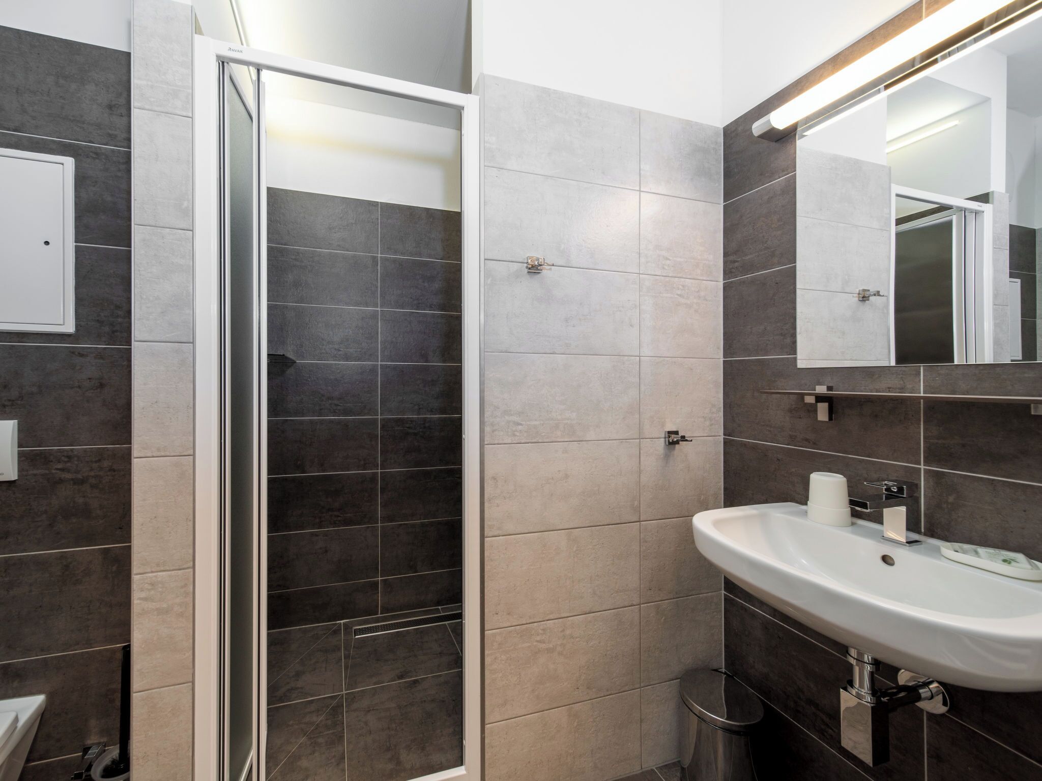 Une salle de bain moderne avec une douche, un lavabo et un miroir.
