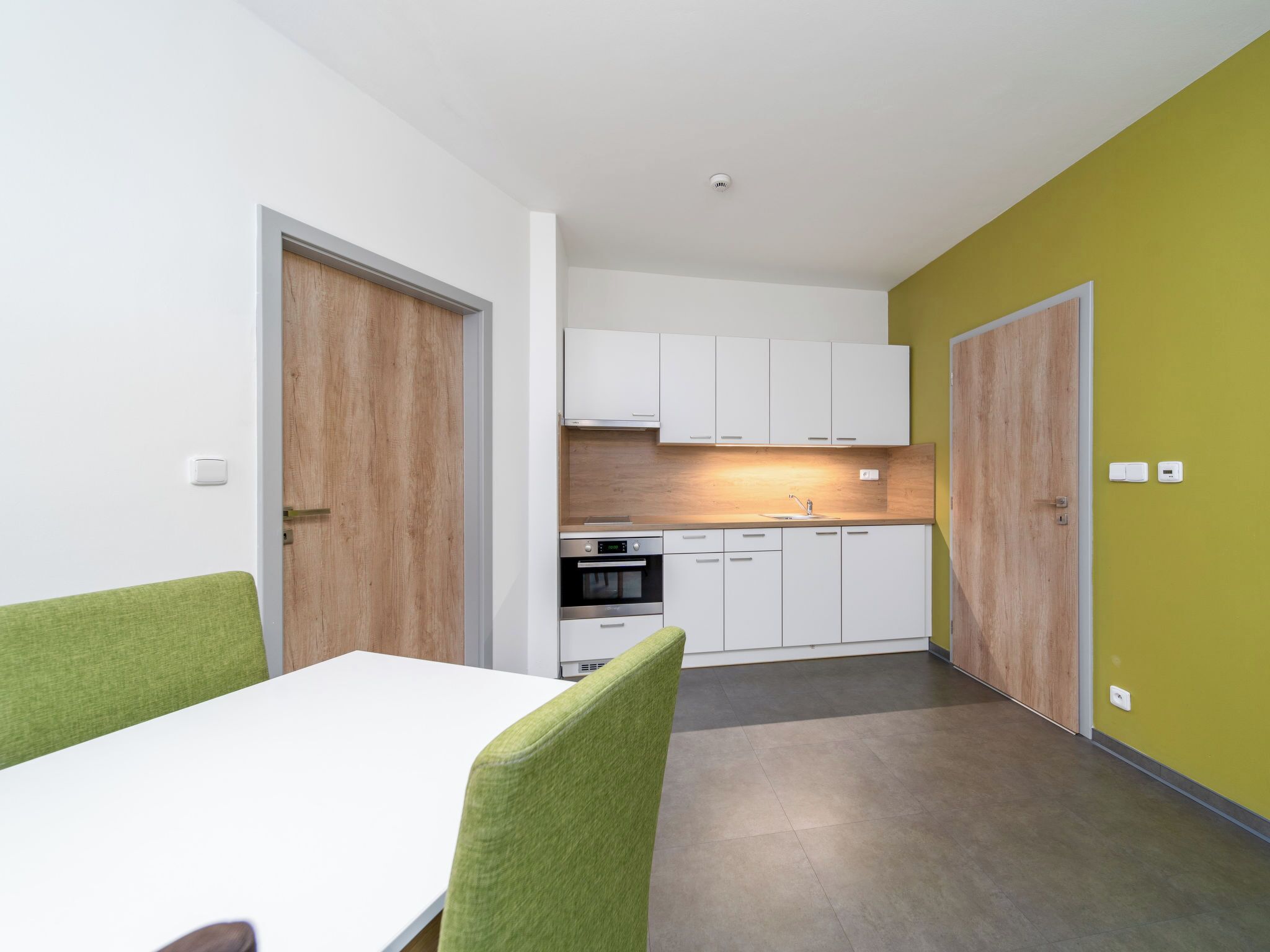A modern kitchen with white cabinets, a built-in oven, and a wooden backsplash.