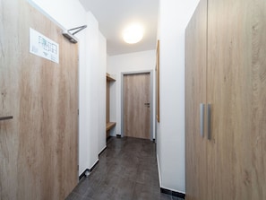 Ein Korridor mit Holztüren, gefliestem Boden und einer Deckenleuchte.