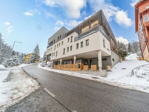 Ein modernes Hotel mit überdachter Einfahrt, einer schneebedeckten Straße und blauem Himmel.