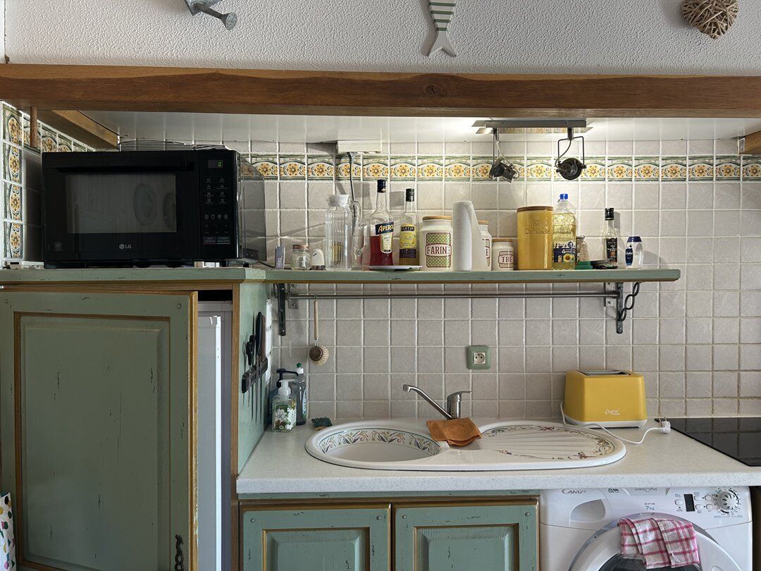 Une cuisine équipée d’un four à micro-ondes, d’un évier et de divers ustensiles de cuisine disposés sur le plan de travail.