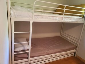 Een stapelbed met een onderbed en een bovenbed, beide met witte beddengoed.
