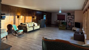 Un espacio habitable amplio con un sofá, una mecedora, una mesa de comedor y un televisor.