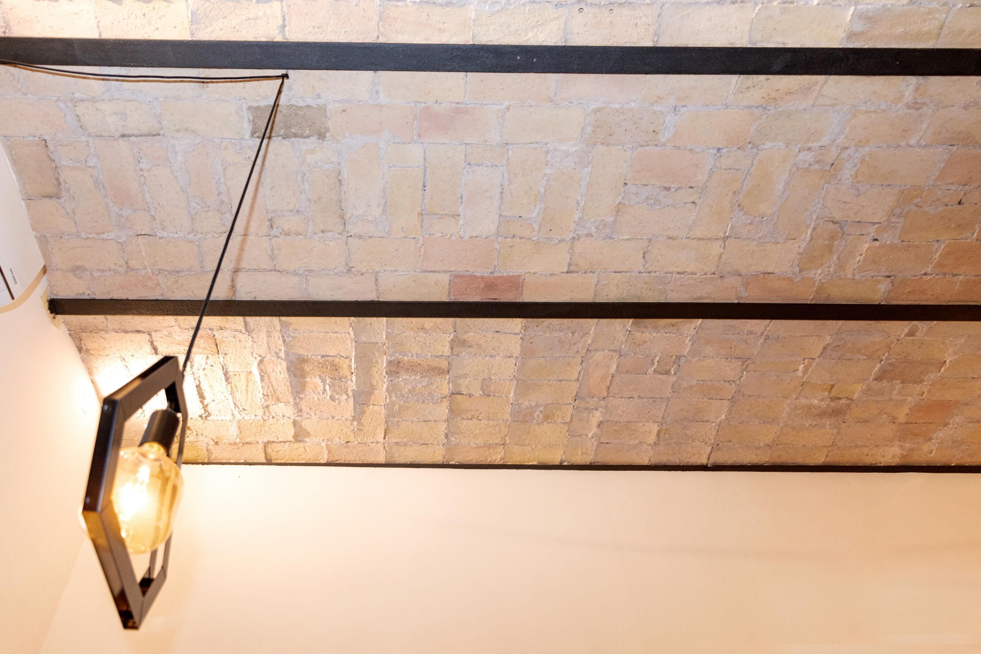 A brick ceiling with exposed beams and a hanging light fixture.