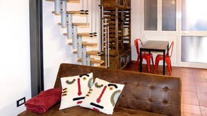 A room with a brown sofa, red chairs, a wooden staircase, and a dining table. - Trastevere Secret Loft (ROMA)