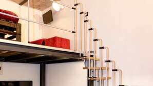 A staircase with metal railings and wooden steps, a sofa, a traffic light, and a television on the wall. - Trastevere Secret Loft (ROMA)